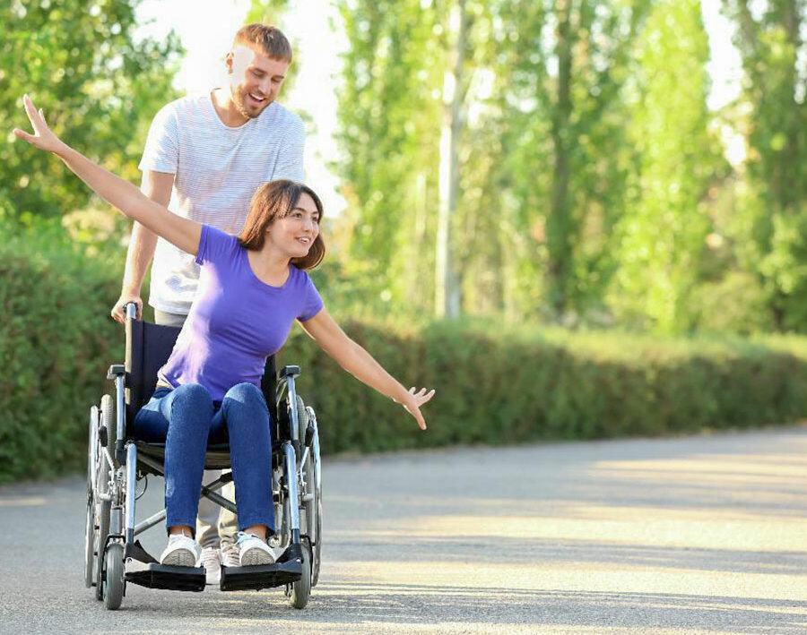 Mann schiebt fröhliche Frau im Rollstuhl